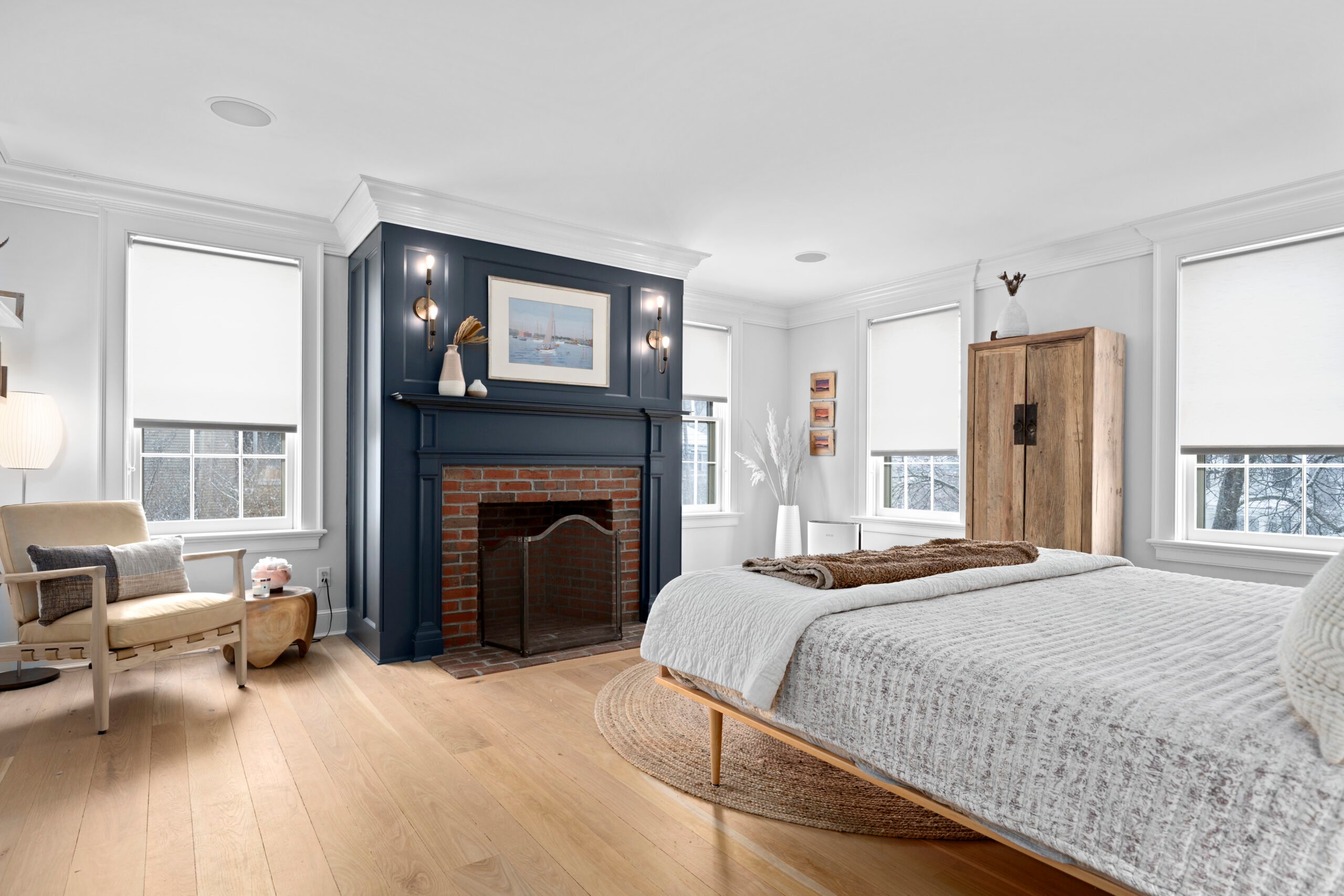 Modern bedroom featuring a cozy bed with textured bedding, a stylish wooden cabinet, and a decorative fireplace, showcasing professional real estate photography for effective property marketing.