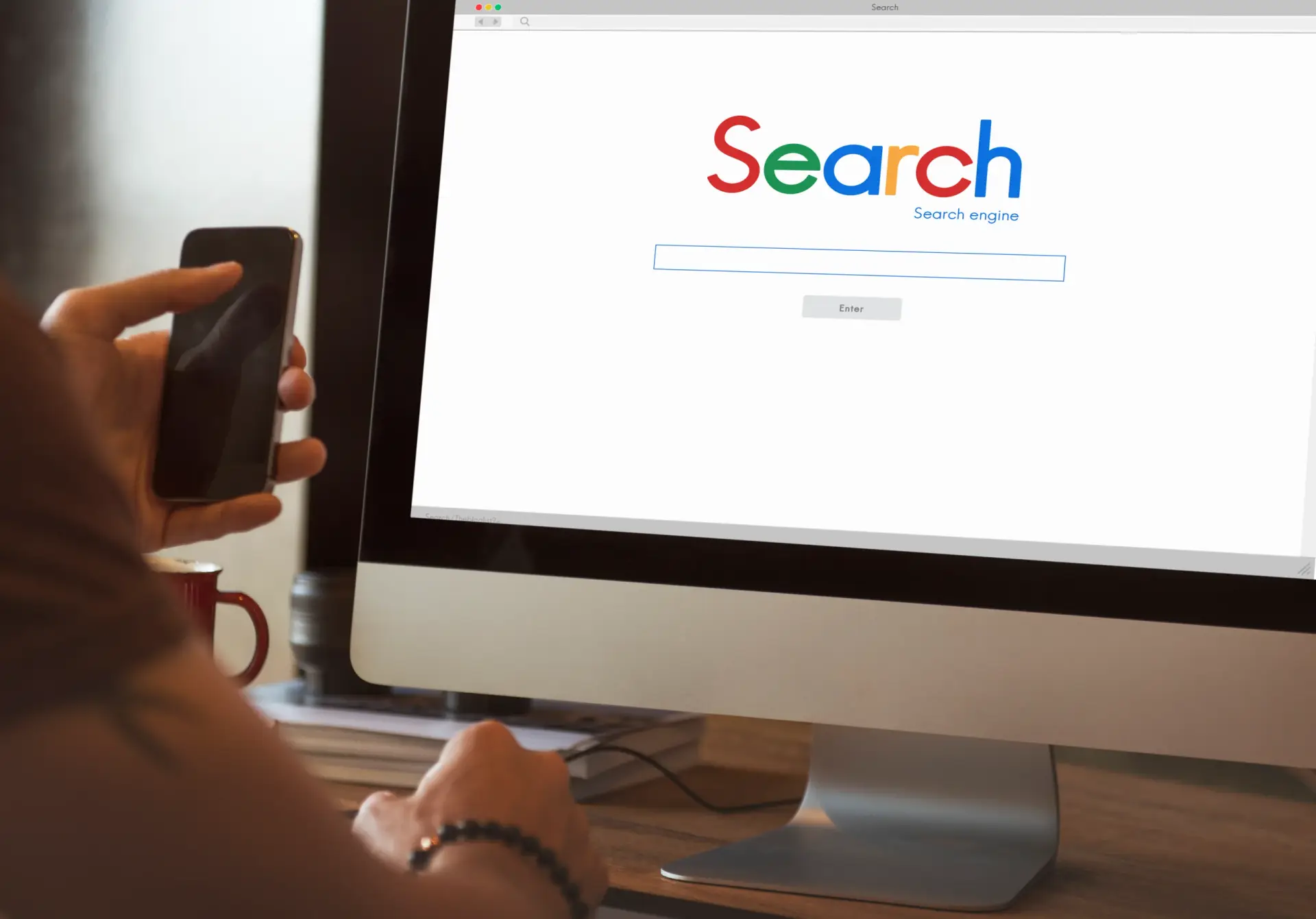 Person holding smartphone while searching for local services on a computer screen displaying a search engine interface.