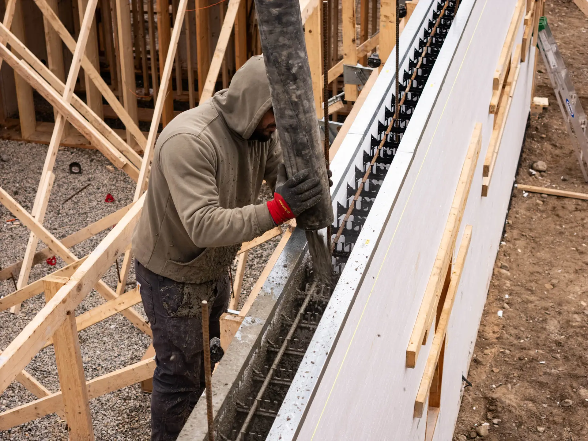 Construction worker pouring concrete into foundation formwork at a building site, illustrating hands-on work in home construction and remodeling.