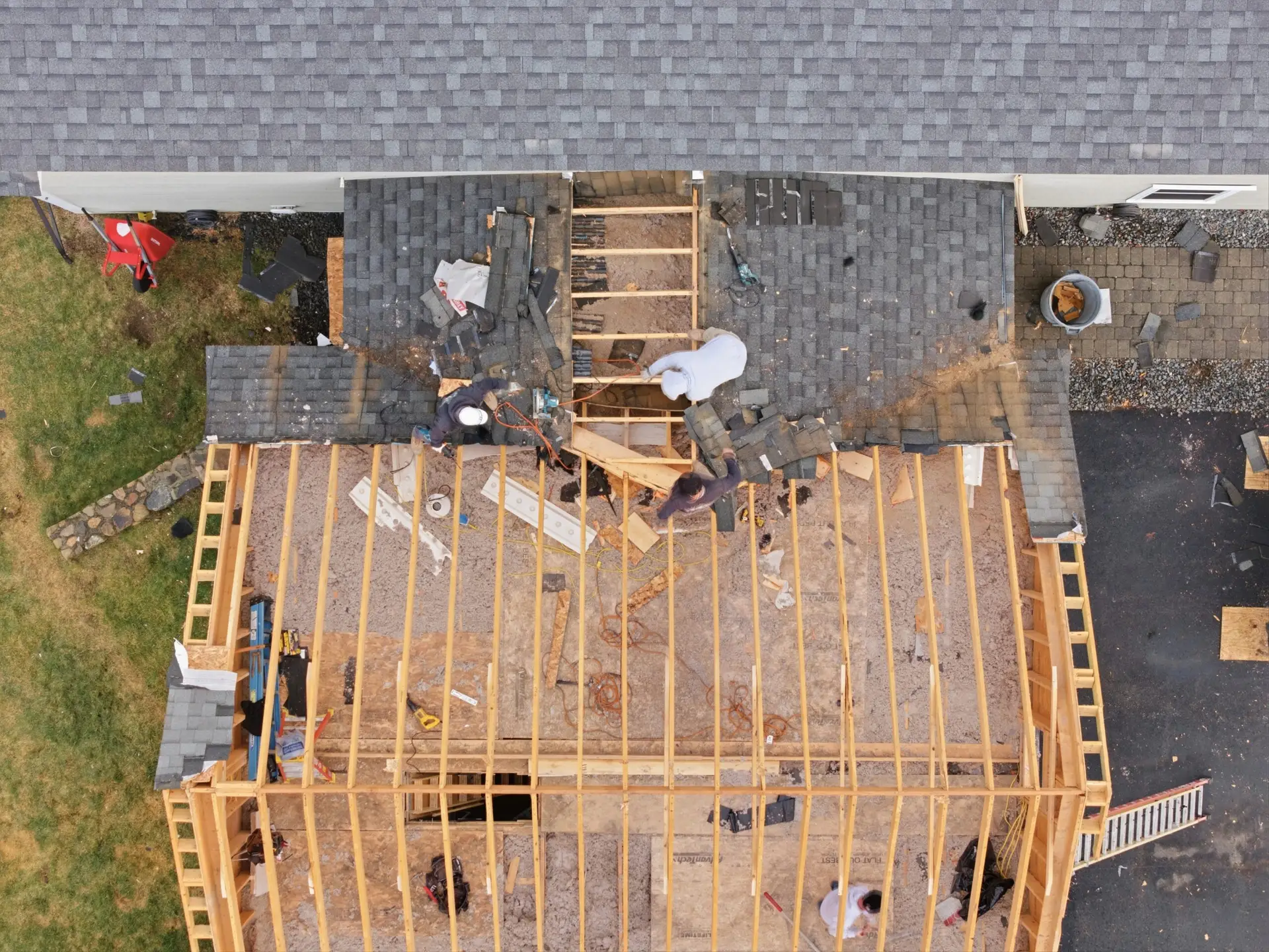 Roofing crew installing shingles on a residential home under renovation, showcasing construction progress and teamwork for contractors.