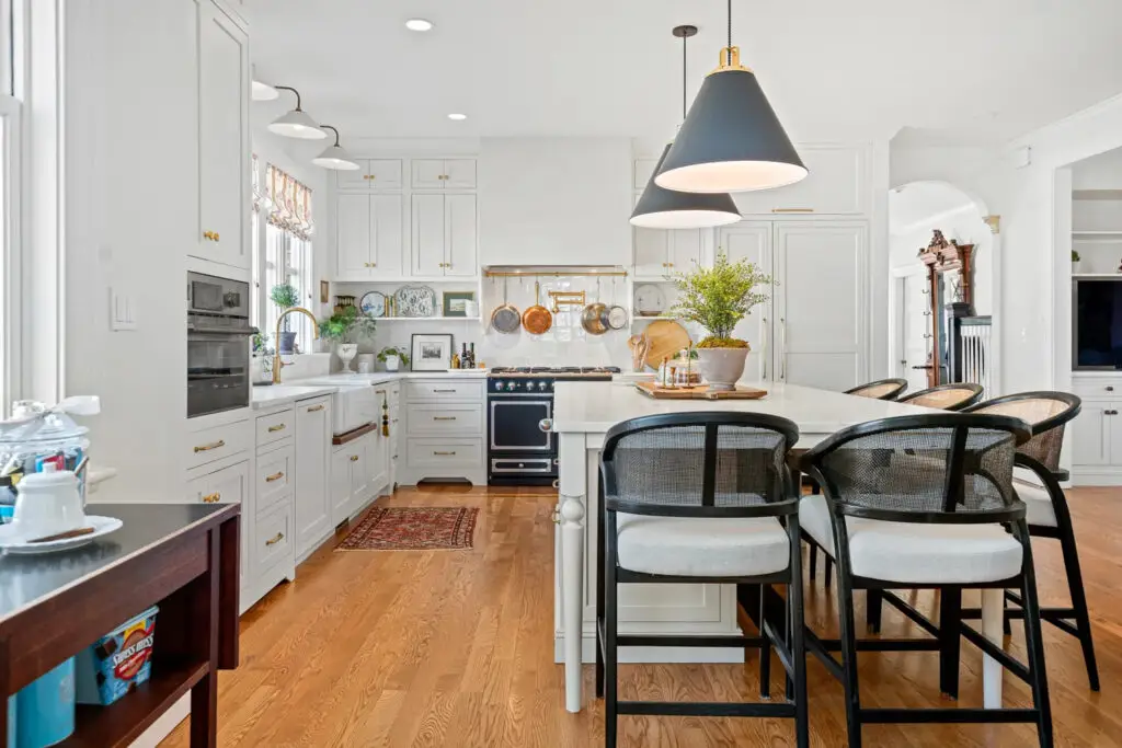 Bright kitchen with white cabinets, large island, and modern pendant lights.