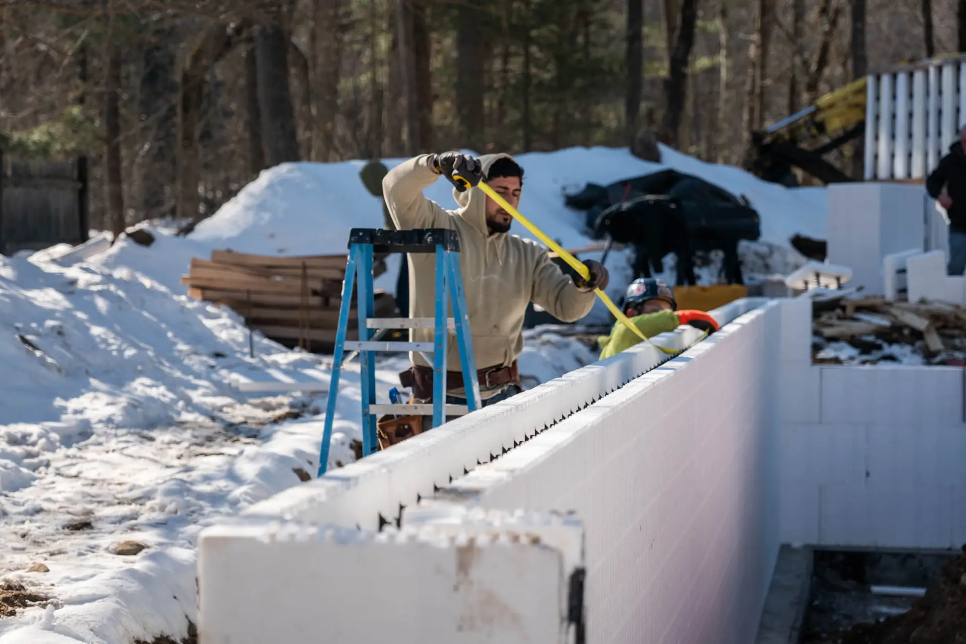 ICF block build on construction jobsite, contractor measuring wall for lasting build.