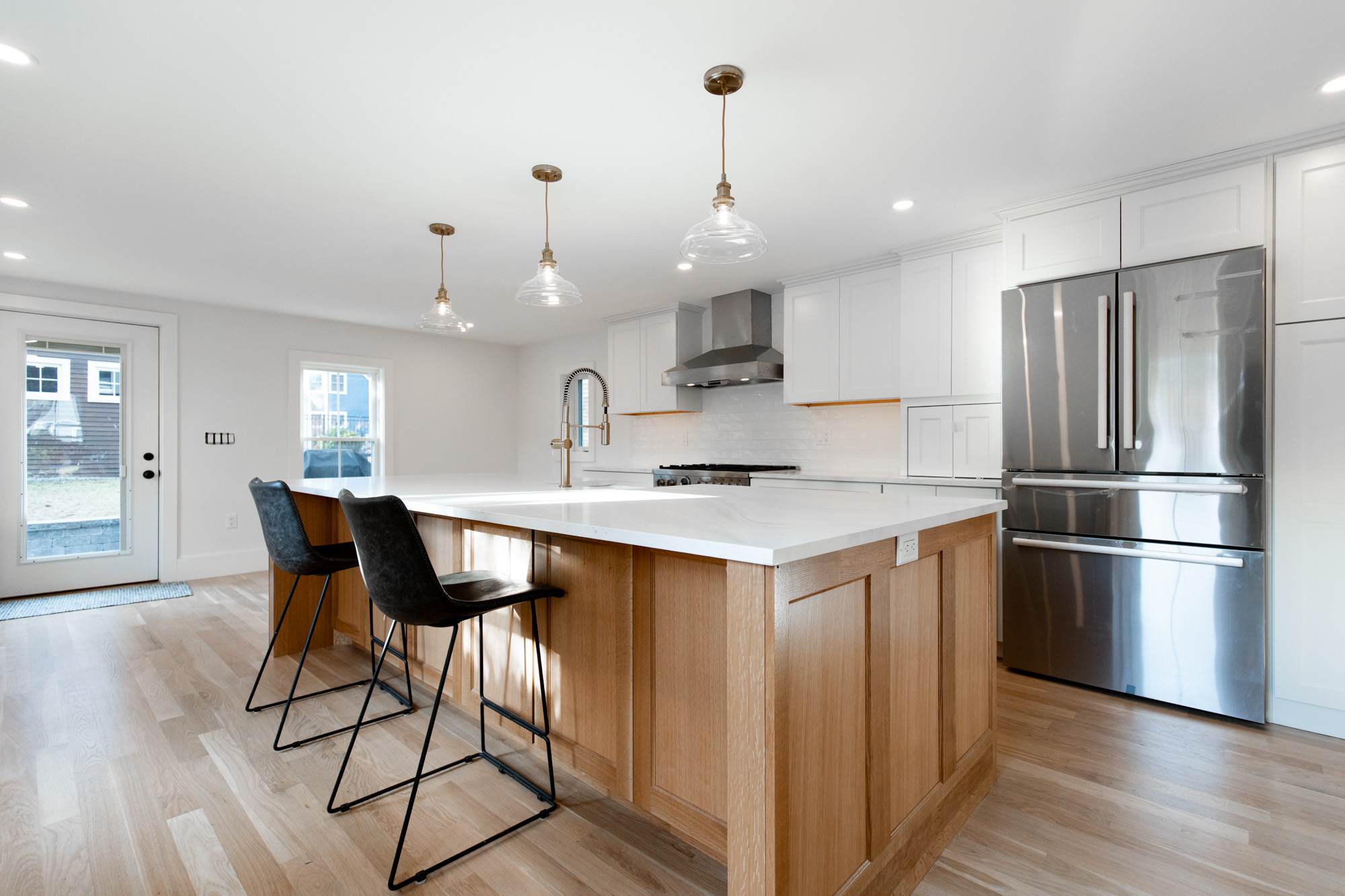 Modern kitchen island design featuring stainless steel appliances and stylish lighting, showcasing cabinetry and millwork
